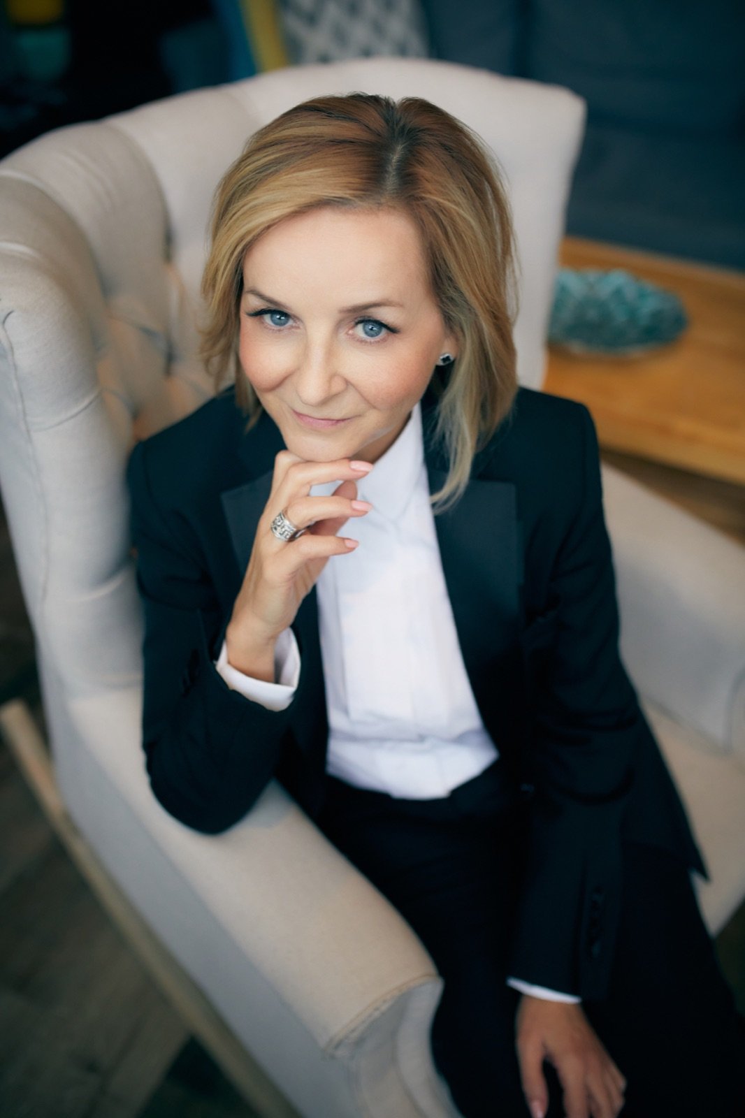 Tracy Quinton seated in a tufted chair, chin on her hand, listening