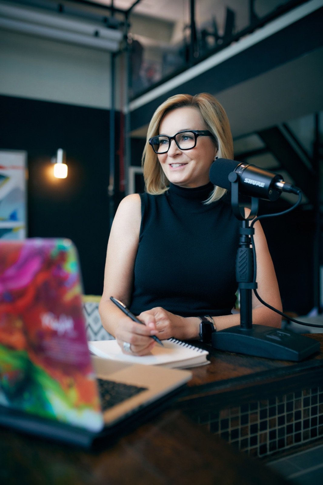 Tracy Quinton at her desk with a notebook and microphone, listening